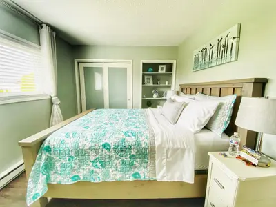 a bedroom with a bed with a blue and white comforter at The Beach House at Deep Bay in Bowser