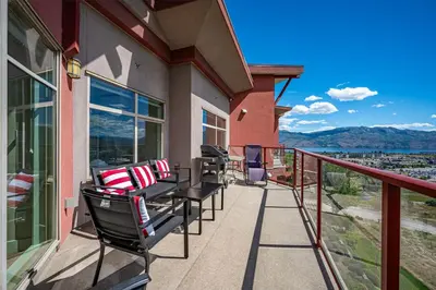 a balcony with chairs and a view of the mountains at Top Floor Apartment at Amenity Rich Resort 406 in West Kelowna