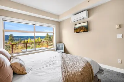 a bedroom with a bed and a large window at Top Floor Apartment at Amenity Rich Resort 406 in West Kelowna