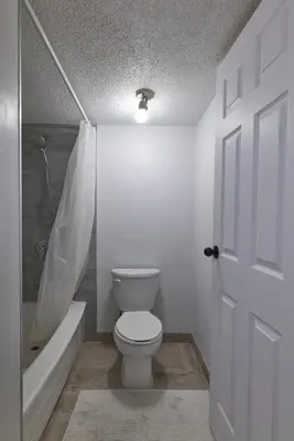 a bathroom with a toilet and a bath tub and a door at Bowness Suites in Calgary
