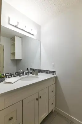 a bathroom with a sink and a large mirror at Bowness Suites in Calgary