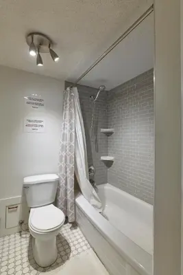 a bathroom with a toilet and a bath tub at Bowness Suites in Calgary