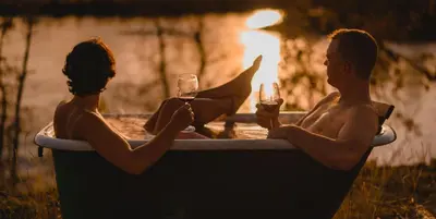 two men sitting in a bath tub with glasses of wine at Yukon River Farm in Whitehorse