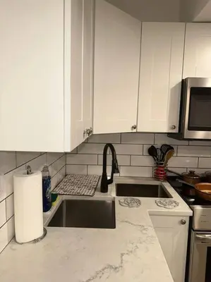 a white kitchen with a sink and a microwave at Brand new 1 Bedroom Basement Suite. Wi-Fi,Netflix in Edmonton