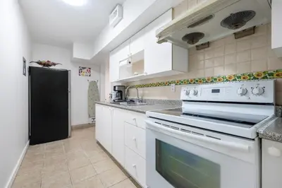 a kitchen with white appliances and a black refrigerator at Luxury Delta 2BD Suit on ground floor in Delta