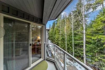 a balcony of a house with a view of the woods at Best ski in ski out condo #3 in Aspens in Whistler