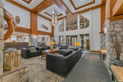 a living room with leather furniture and a stone wall at Best ski in ski out condo #3 in Aspens in Whistler