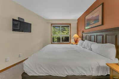 a bedroom with a large white bed and a window at Best ski in ski out condo #3 in Aspens in Whistler