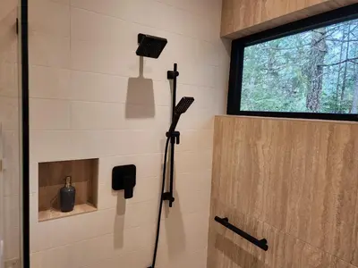 a shower in a tiny bathroom with a window at The Shed at Moon Dance in Madeira Park
