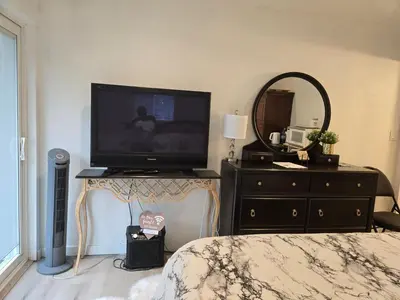 a bedroom with a television and a dresser with a mirror at Private master bedroom in a farmhouse in Nanoose Bay