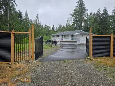 a driveway with a gate in front of a house at Private master bedroom in a farmhouse in Nanoose Bay