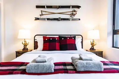 a bedroom with a bed with red and black pillows at Monashee Sunshine - Condo with Private Hot Tub in Revelstoke