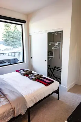 a bedroom with a bed and a large window at Monashee Sunshine - Condo with Private Hot Tub in Revelstoke