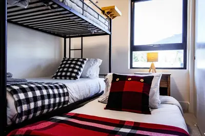 two beds in a room with a bunk bed at Monashee Sunshine - Condo with Private Hot Tub in Revelstoke