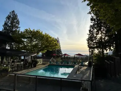 a swimming pool with chairs and umbrellas at Seymour Private Bedroom, Ensuite Bathroom with Shared Pool, Hot Tub with Views in North Vancouver