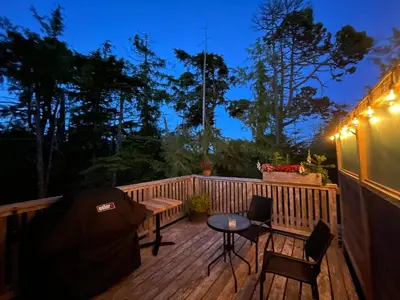 a deck with a table and chairs at night at Brown's Beach Guest Suite in Ucluelet