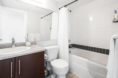 a bathroom with a toilet and a sink and a bath tub at GardenView Modern Condo with Parking, Gym, Pool, AC in Vancouver