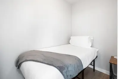 a small bed in a room with white walls at GardenView Modern Condo with Parking, Gym, Pool, AC in Vancouver