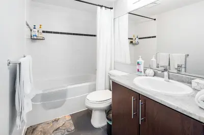 a white bathroom with a sink and a toilet at GardenView Modern Condo with Parking, Gym, Pool, AC in Vancouver