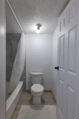 a bathroom with a toilet and a bath tub and a door at 2bedroom suite w/ great access into & out the city - 7818 in Calgary