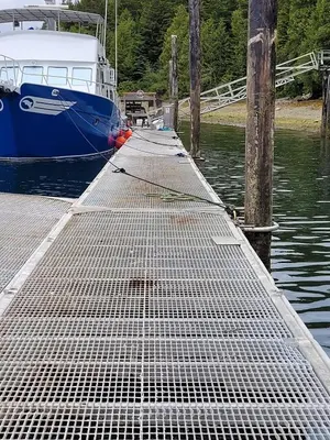 a boat is docked next to a dock with a boat at Argo's Landing in Bamfield