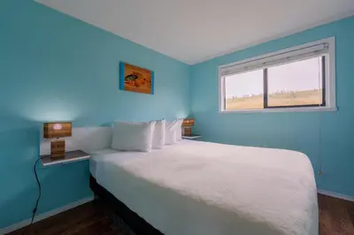 a blue bedroom with a bed and a window at The Cabins at Alert Bay in Alert Bay