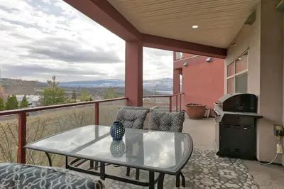 a patio with a glass table and chairs on a balcony at Stay In The Okanagan - Copper Sky, West Kelowna in West Kelowna