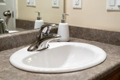 a white sink in a bathroom with two soap dispensers at Polar Peaks Hot Tub Pool Gas Fireplace in Radium Hot Springs