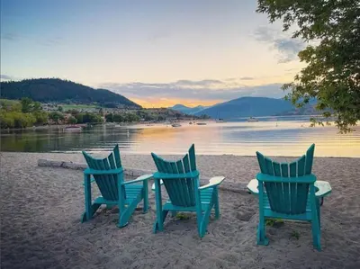 three chairs and a table on the beach at Top Floor Lakeshore Views Near Skiing in Vernon