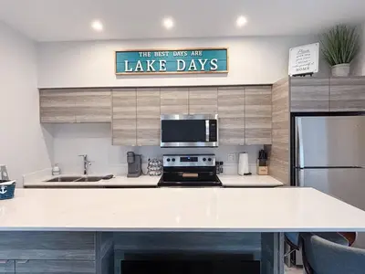 a kitchen with a white counter top and a sign that reads the best ways are at Top Floor Lakeshore Views Near Skiing in Vernon