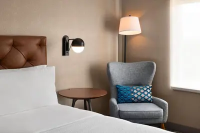 a bedroom with a bed and a chair and a lamp at Four Points by Sheraton Penticton at the Convention Centre in Penticton