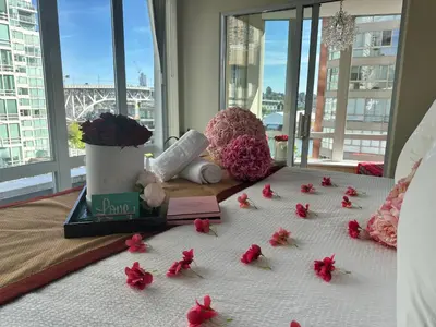 a pile of flowers on a bed with a window at Penthouses of Beach Ave in Vancouver