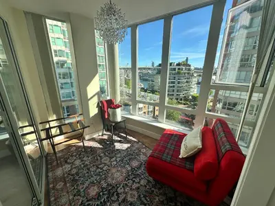 a living room with a red couch and large windows at Penthouses of Beach Ave in Vancouver