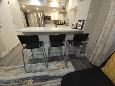 a kitchen with a counter with four bar stools at Cozy 2 Bedroom Suite, Queen Beds, Near the Airport in Edmonton