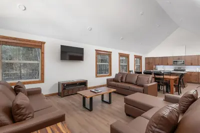 a living room with two couches and a kitchen at The Evergreen Cabin in Valemount