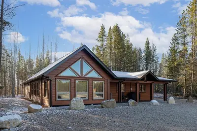 a cabin in the woods with rocks in front of it at The Evergreen Cabin in Valemount