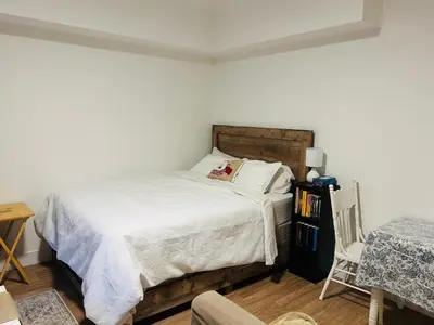 a bedroom with a bed with white sheets and a chair at Victoria private studio suite in Victoria
